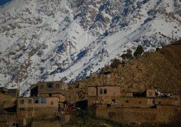 brown concrete building near snow covered mountain during daytime