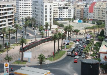 A city street filled with lots of traffic next to tall buildings
