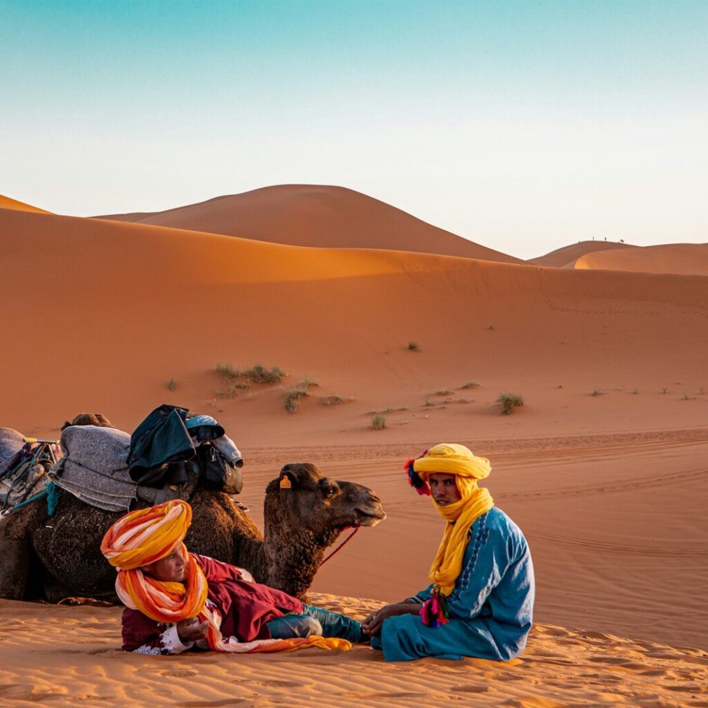 man in yellow robe sitting on brown sand during daytime